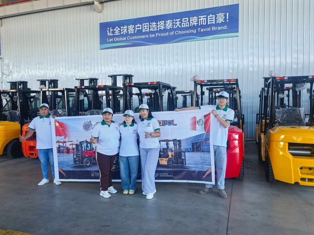 Peruvian dealer team holding a joint banner in front of Tavol forklifts